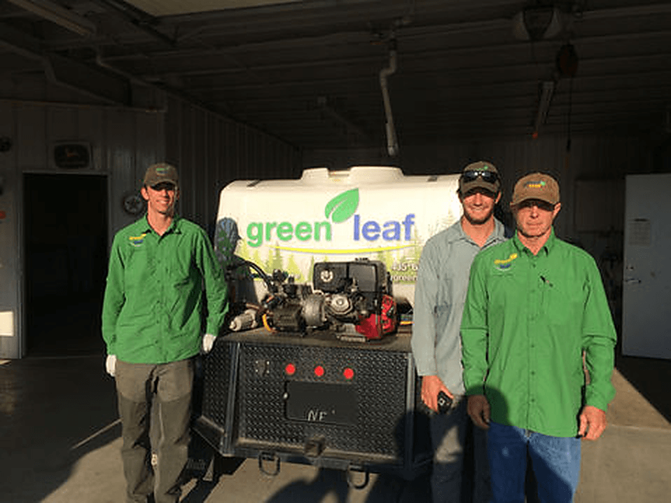 Greenleaf crew members standing beside a branded service truck